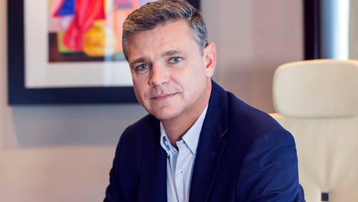 Arnaud Lagesse in a navy blazer seated at his executive office desk